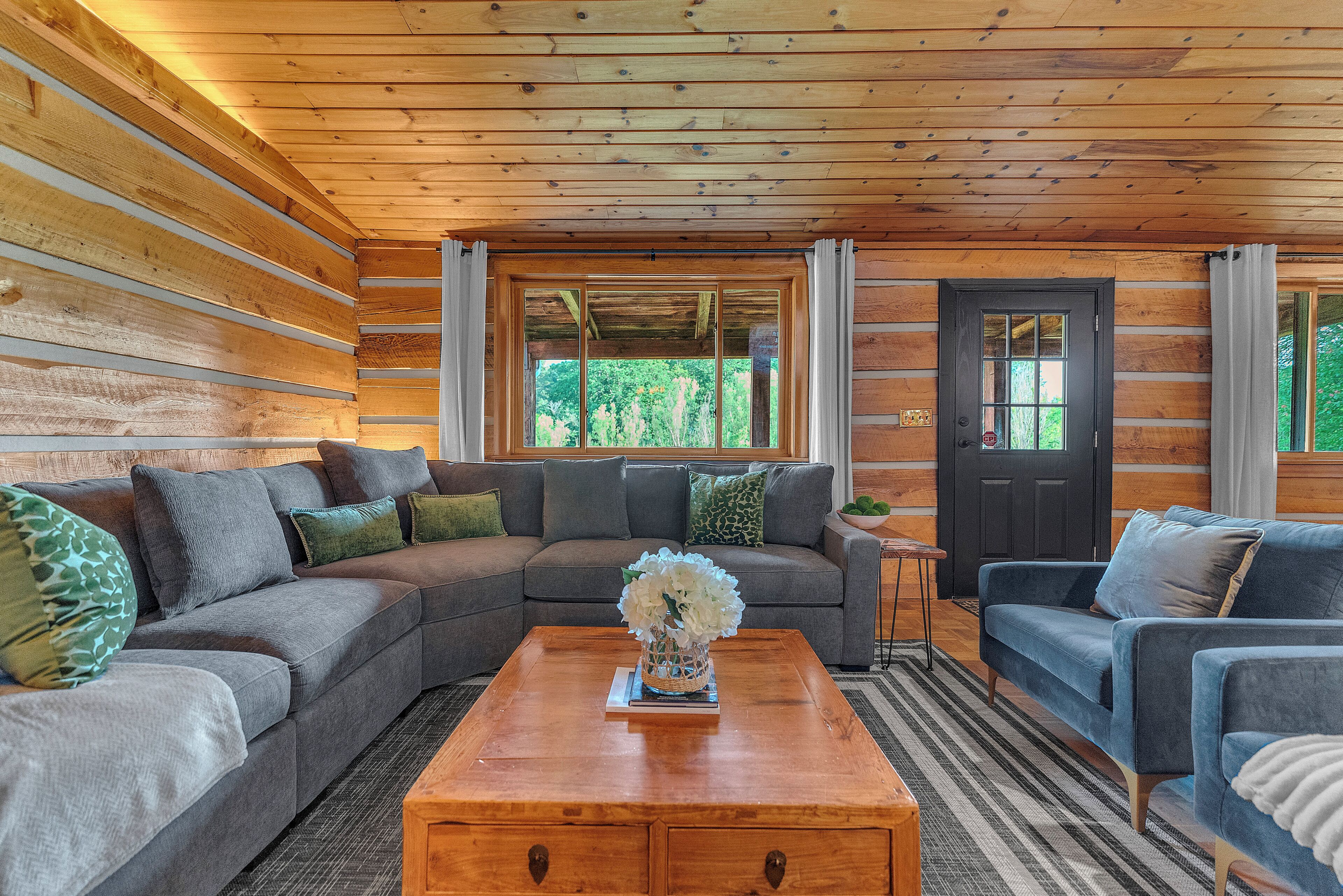 A log cabin interior with a sectional sofa, a coffee table, and a door with a window.