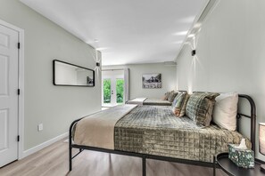 Un dormitorio con cama, mesita de noche y ventana con vista a zonas verdes.
