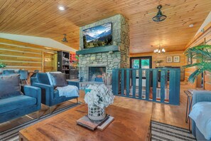 A cozy living room with a stone fireplace, wooden ceiling, and comfortable seating.