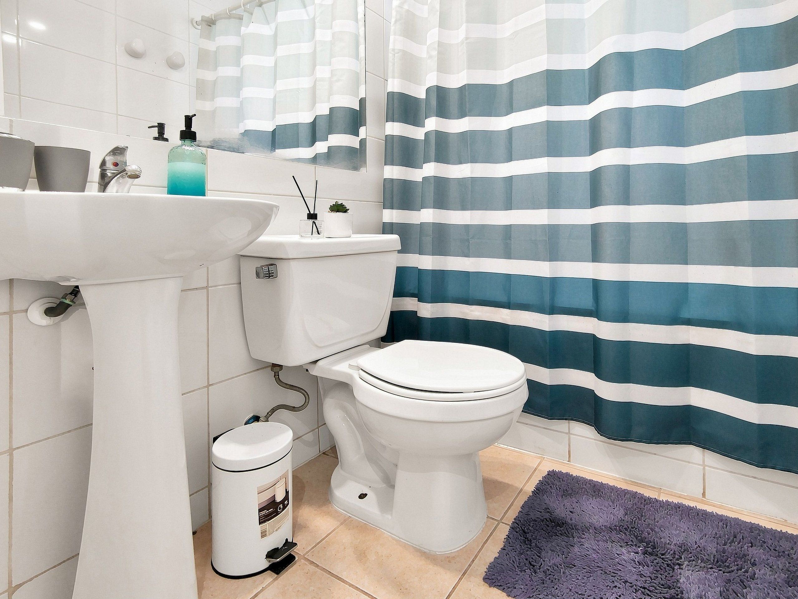 Een badkamer met een wit wastafel, toilet en een prullenbak.