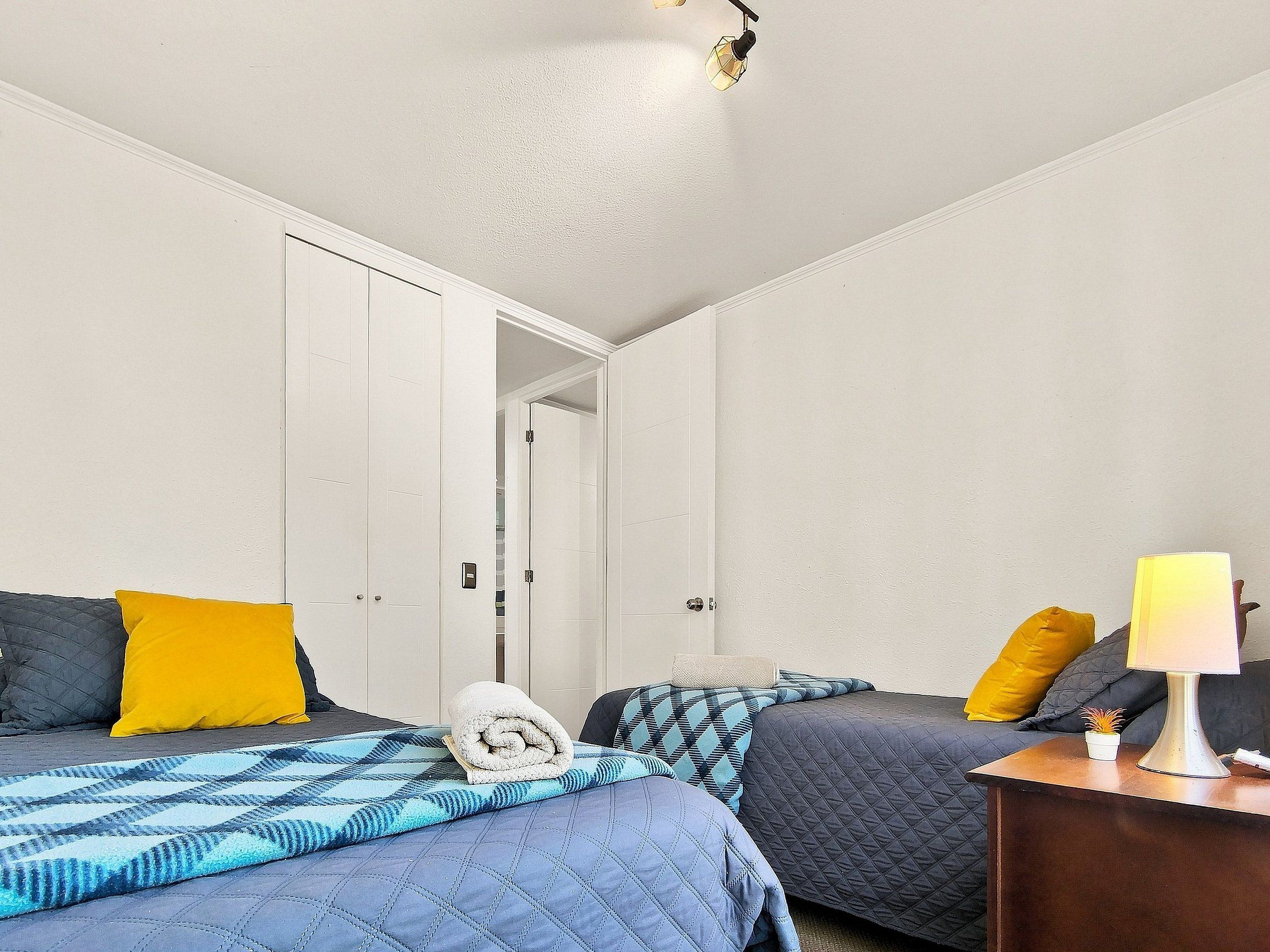 Une chambre à coucher comprenant un lit, une table de chevet, une lampe et une porte donnant sur une autre pièce.