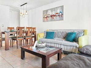 A living room with a dining table, chairs, a sofa, and a coffee table.