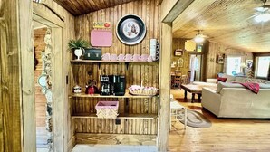 Ein gemütliches Zimmer mit Holzwänden, einer Couch, einem Couchtisch und Regalen mit verschiedenen Gegenständen.