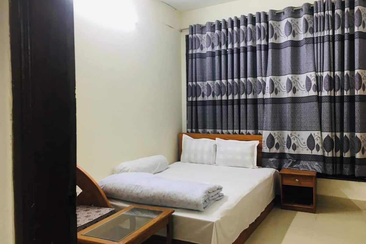 A bedroom with a bed, bedside tables, and a curtain with a leaf pattern.