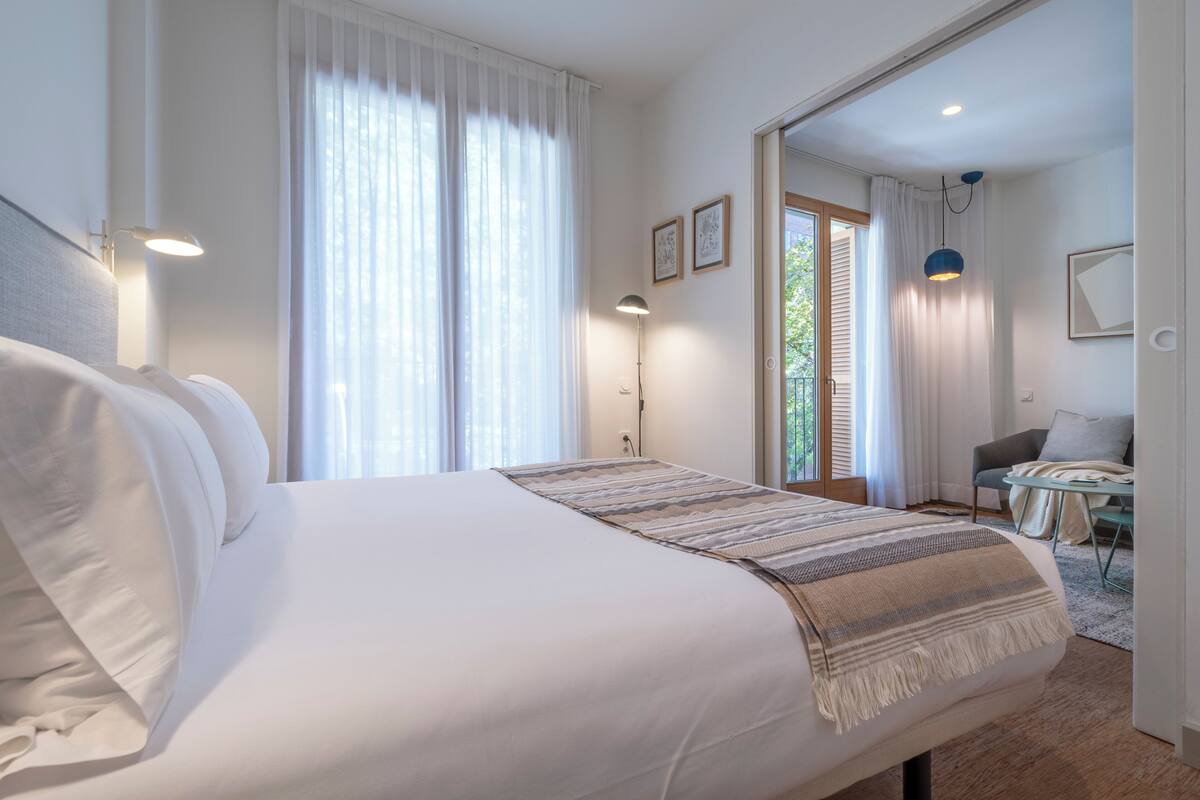 Moderni hotellihuone, jossa on suuri sänky, työpöytä ja näkymä ulos.