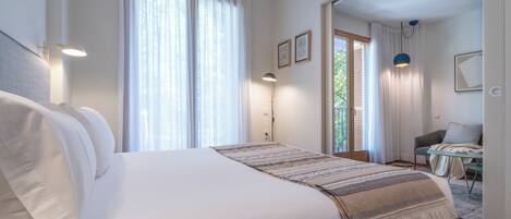 Habitación de hotel moderna con una cama grande, un escritorio y vistas al exterior.