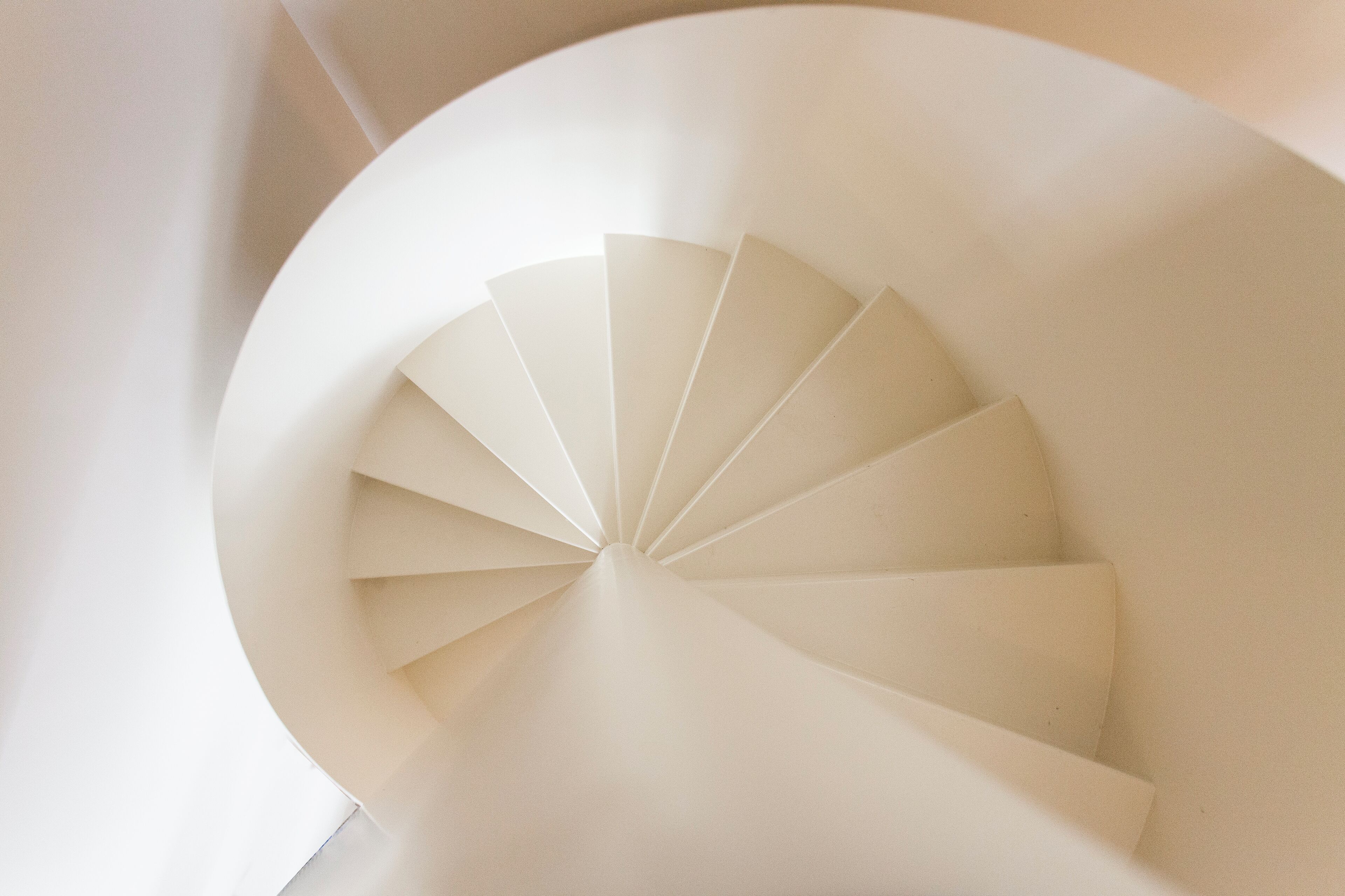 Un escalier en colimaçon au design moderne, fabriqué à partir de matériaux blancs.