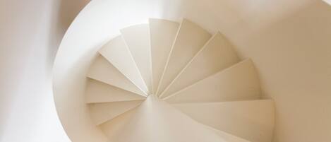 Un escalier en colimaçon au design moderne, fabriqué à partir de matériaux blancs.