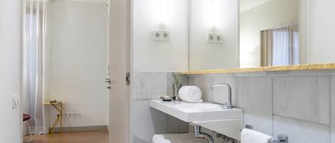 A modern bathroom with a white sink, mirror, and towel rack.