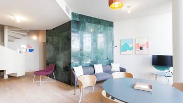 Een moderne vergaderruimte met een ronde tafel, diverse stoelen, een bank en een televisie.