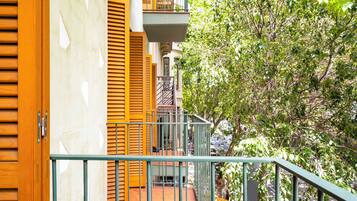A balcony with a view of a tree and a building.