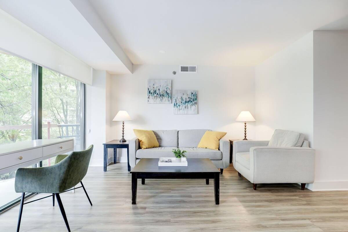 A modern living room with a sofa, two armchairs, a coffee table, and two lamps.