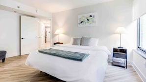 A modern bedroom with a large bed, bedside lamps, and a window. - Premium A-Location Apartment (Arlington)