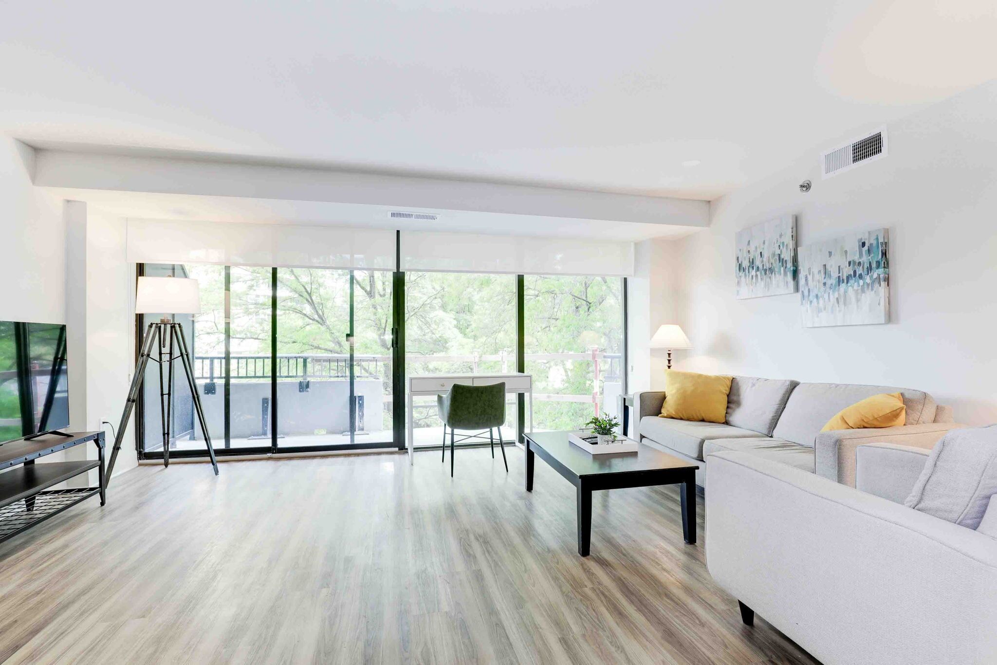 A modern living room with a sofa, coffee table, and a desk with a lamp.
