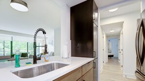 A modern kitchen with a large sink, stainless steel appliances, and a wooden cabinet. - Premium A-Location Apartment (Arlington)