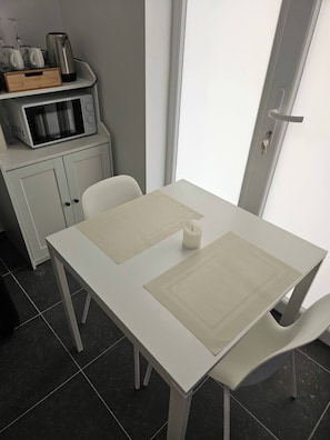 A white table with two placemats, a microwave, and a cabinet with kitchenware. - Suite With Private Jacuzzi (Seraing)