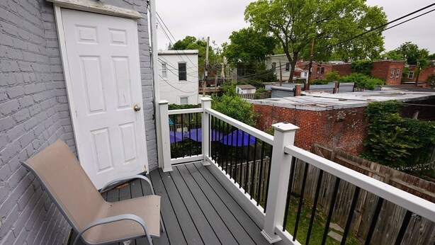 A wooden deck with a white door and a bench. - Four Bedroom House Near Sports & Museums (Washington)