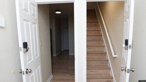 A hallway with wooden flooring and white walls, leading to a staircase. - Four Bedroom House Near Sports & Museums (Washington)