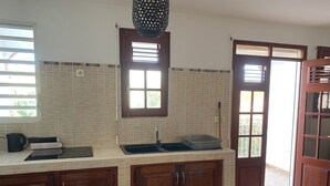 Una cucina con zoccolo in ceramica, mobili in legno, un lavello e una finestra con persiane.