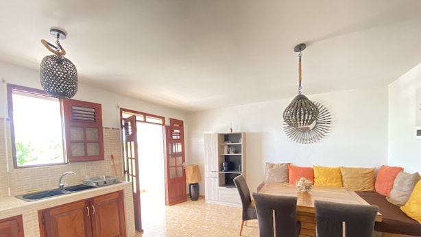 Un'ampia cucina con zona pranzo, mobili in legno, pavimento piastrellato e un moderno lampadario.
