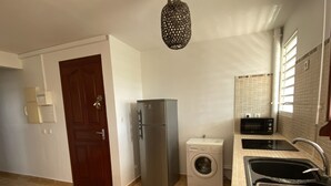 Una cucina con frigorifero, lavatrice, lavello e lampadario.