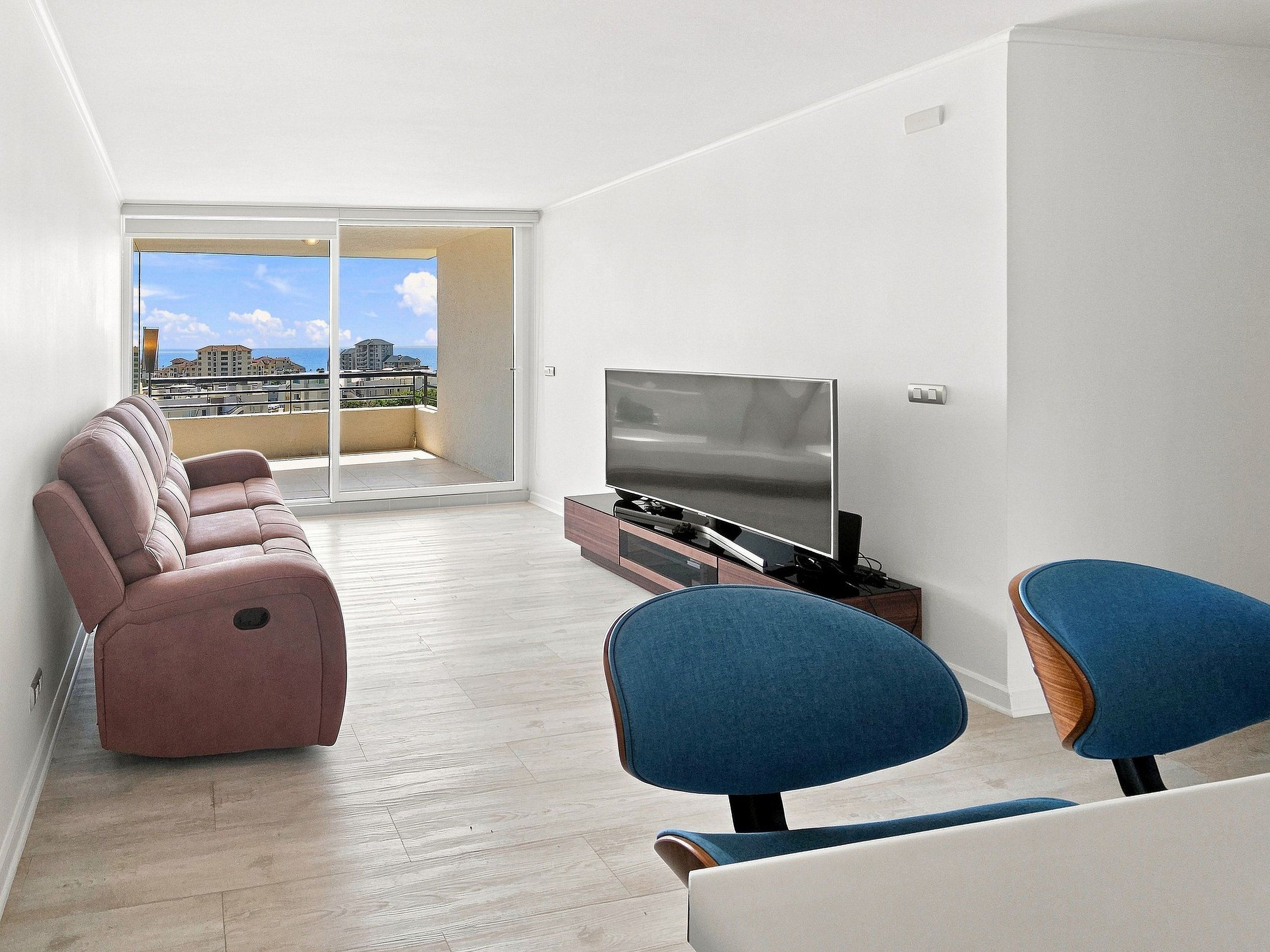 Una sala moderna con un conjunto de sofá, un televisor de pantalla plana y dos sillones.