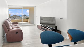 Un saló modern amb un sofà, un televisor de pantalla plana i dues butaques.