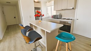 A modern kitchen with a central island, bar stools, and a sink. - Oceana Suites Papudo (Papudo)