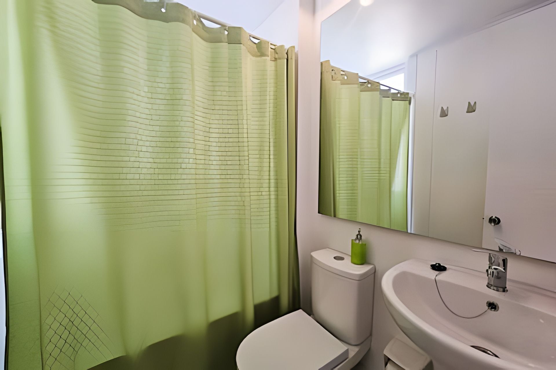 A bathroom with a toilet, sink, and a large mirror.