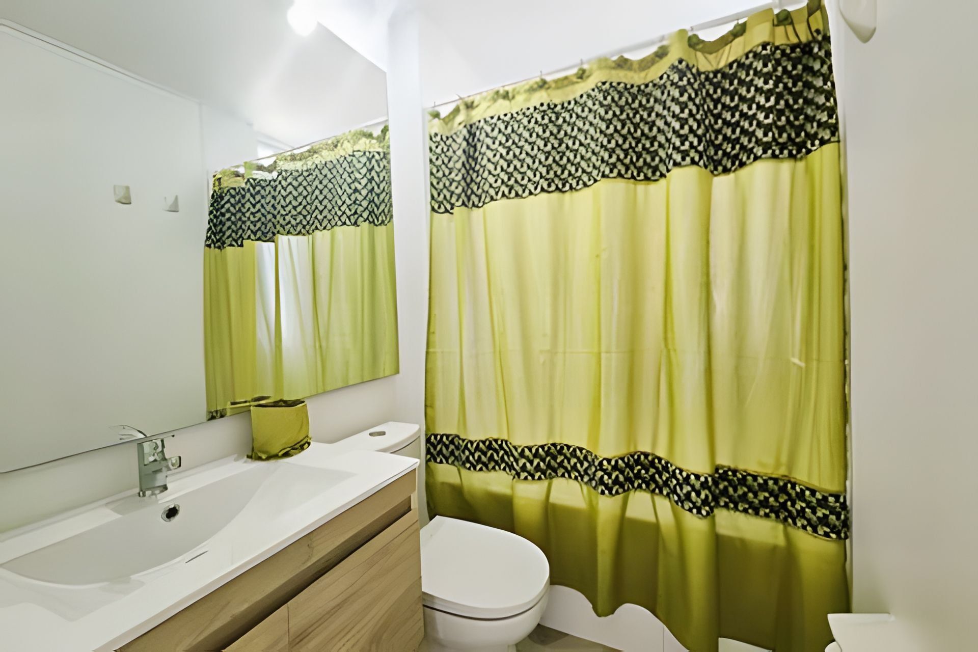 A bathroom with a white sink, mirror, and toilet.