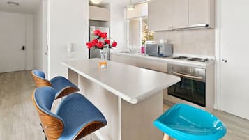A modern kitchen with a central island, bar stools, and a microwave.
