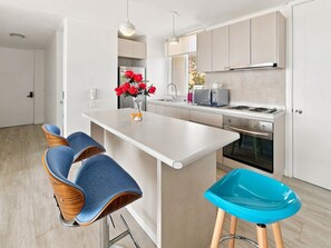 Eine moderne Küche mit Kochinsel, Barhocker und Mikrowelle.