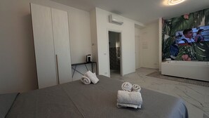 A hotel room with a bed, a bathroom, and a TV displaying a movie scene. - Puglia Promenade Apartment 5 (Bari)