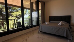 A bedroom with a bed, a view of a balcony, and a chair. - Puglia Promenade Apartment 5 (Bari)