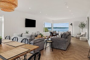 Relax in this stylish living room with a large dining table, comfortable sofa, and flat-screen TV.