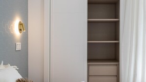 A room with a built-in wardrobe, a wall-mounted light fixture, and a curtain.