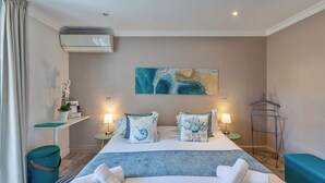 Een hotelkamer met een bed, nachtkastjes, een hangplank, een wandairconditioner en een schilderij.