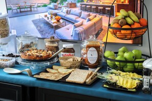 Una mesa de bufé con diversos alimentos, como pan, frutas y salsas.