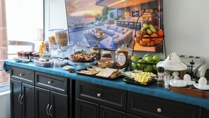 Een ontbijtbuffet met diverse gerechten en een groot raam met uitzicht op een moderne leefruimte.
