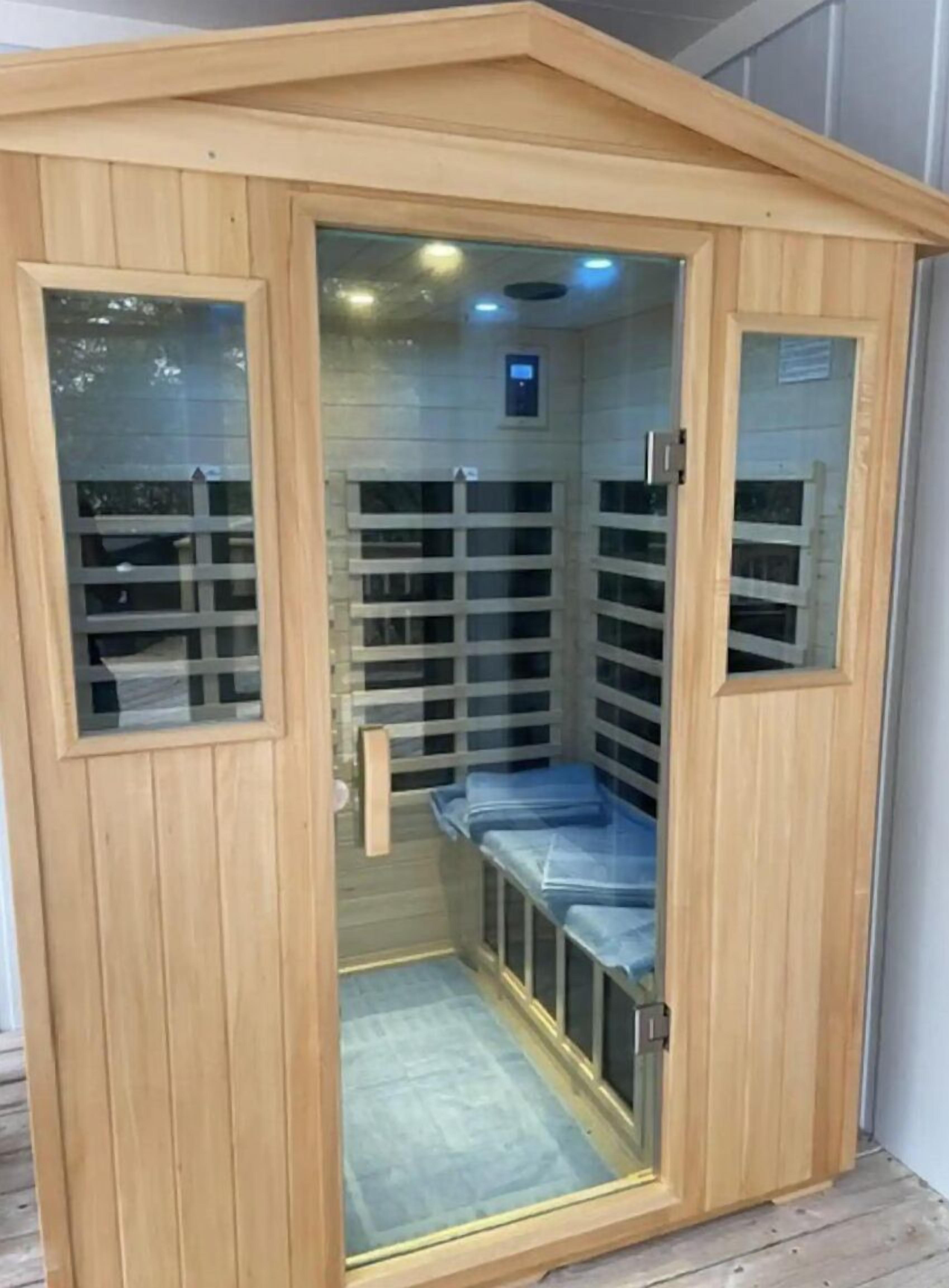 A sauna with a wooden exterior, glass panels, and a bench inside.