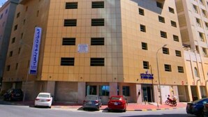 Un hotel de varios pisos con un llamativo frente de vidrio azul y una sección inferior color beige.