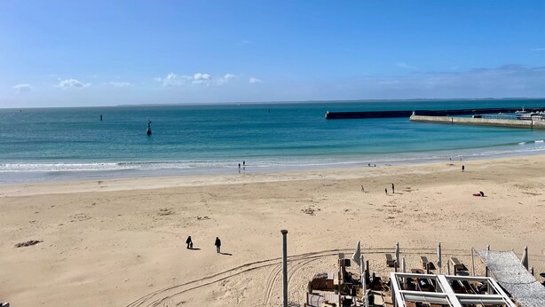A beach with a pier extending into the sea, a sandy shore, and a few people walking. - "les Yeux en Bleu"- 2 ch- Magnifique vue sur la Grande Plage (Quiberon)