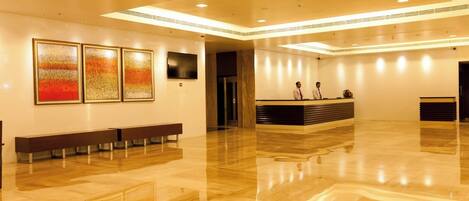 A spacious lobby with a polished wooden floor, a reception desk, and three framed artworks on the wall.