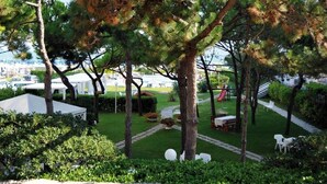 A well-maintained garden with pathways, seating areas, and a tented section, likely for an event or gathering. - Hotel Reno (Jesolo)