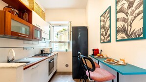 A compact kitchen with a window, a black refrigerator, and a dining area with a table and chairs. - Genteel Home Contessa Matilde II (Pisa)
