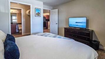Un dormitorio con una cama grande, un aparador y un televisor que muestra un paisaje.