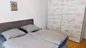 Un dormitorio con cama, almohadas, una obra de arte en la pared y un armario de madera.