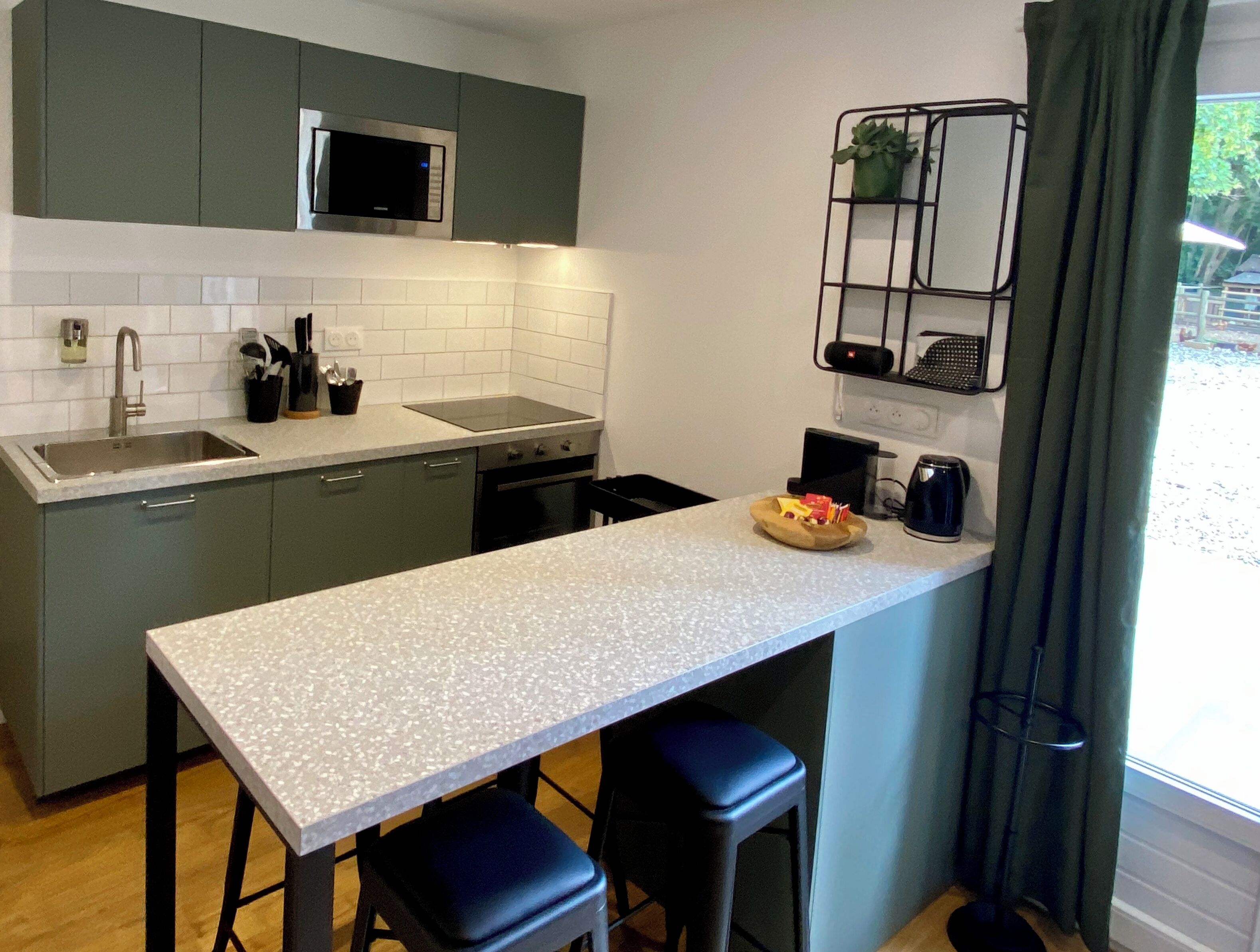 Una cocina moderna con armarios grises, una encimera blanca y un taburete negro.