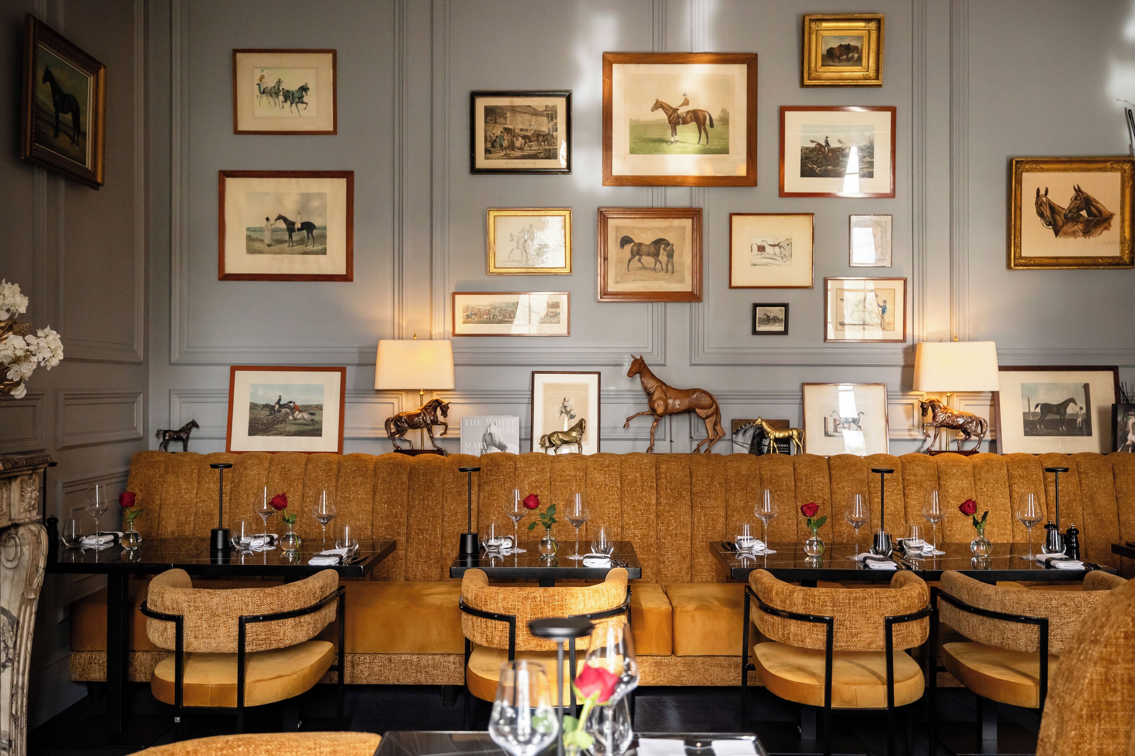 A dining area with a long table, cushioned seating, and framed artwork on the wall.