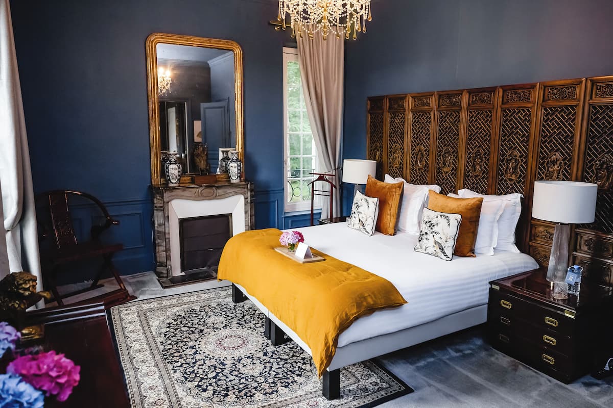 Um quarto com uma cama grande, um espelho, uma lareira e uma mesa de cabeceira.